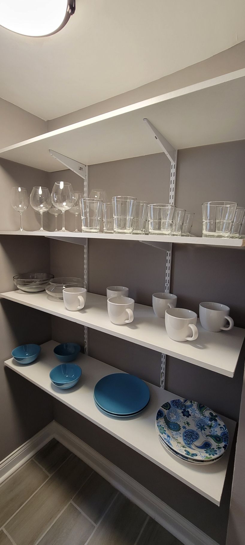 A pantry with shelves filled with plates , cups , and glasses.