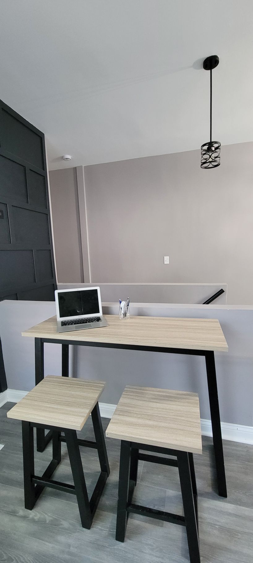 A wooden table with two stools and a laptop on it.