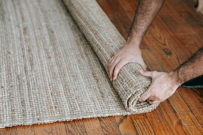 Man rolling up old carpet for flooring and carpet removal service.