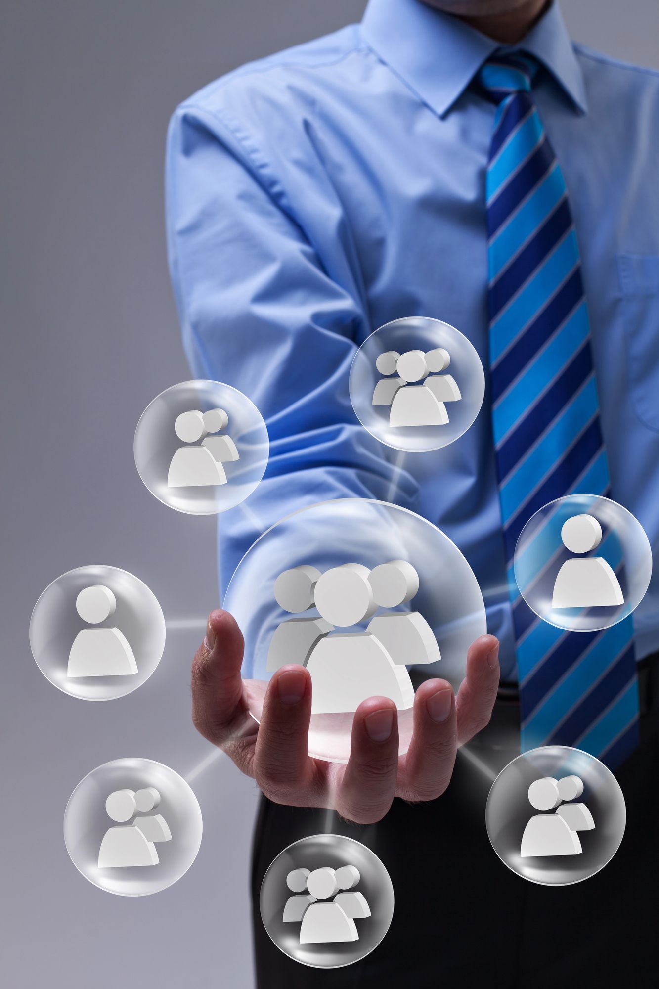 Hombre con camisa azul y corbata sosteniendo esferas brillantes con íconos de personas, que representan redes o conexiones.