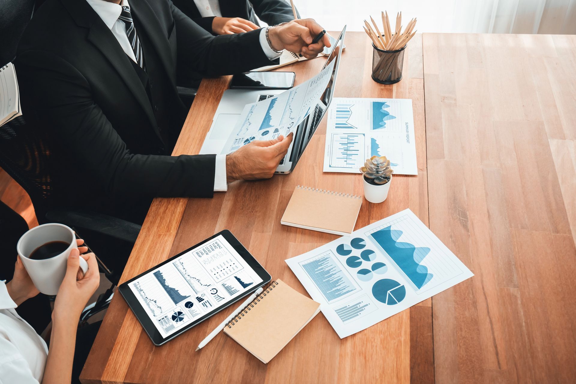 Equipo de negocios revisando gráficos y datos en una mesa de madera.
