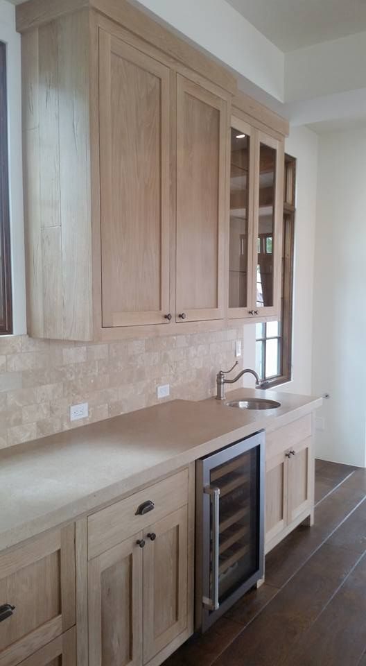 A kitchen with wooden cabinets , a sink , and a wine cooler.