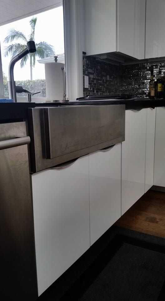 A kitchen with white cabinets and a stainless steel sink.