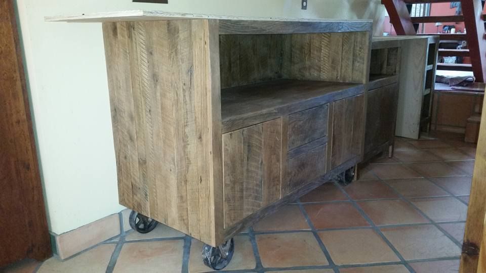 A wooden cabinet with wheels is sitting on a tiled floor in a room.