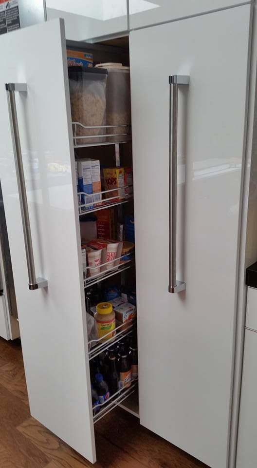 A pantry in a kitchen with two doors open and lots of food in it.