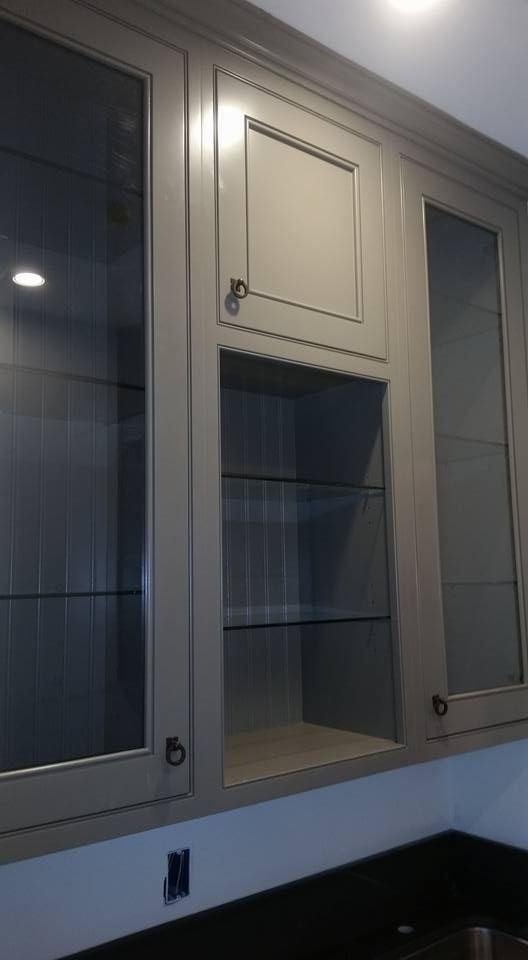 A kitchen with gray cabinets and glass doors