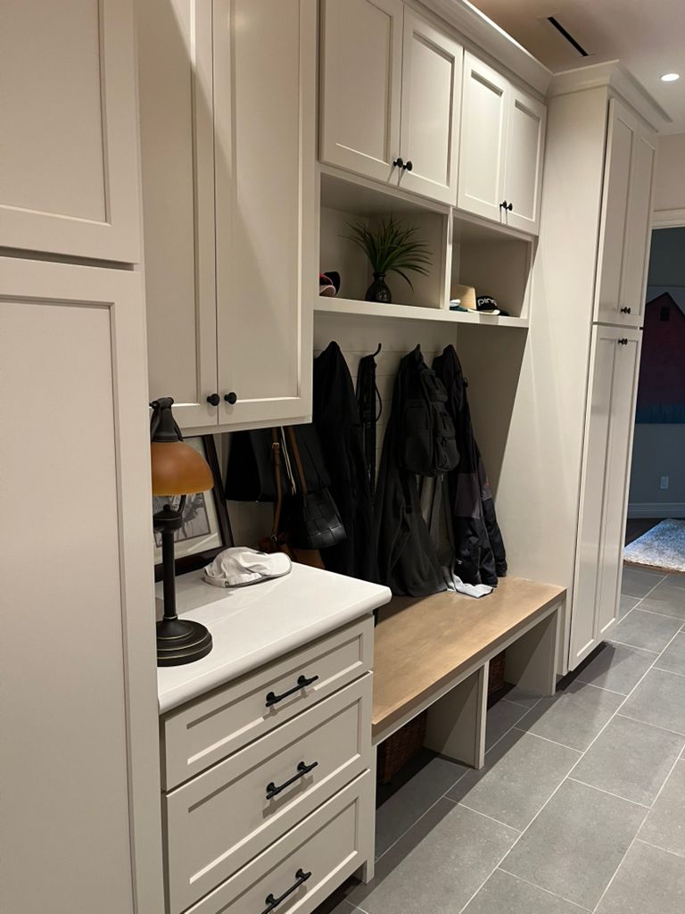 A hallway with white cabinets and a wooden bench.