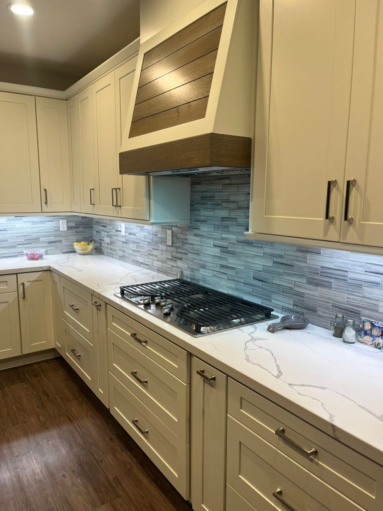 A kitchen with white cabinets and a stove top oven.