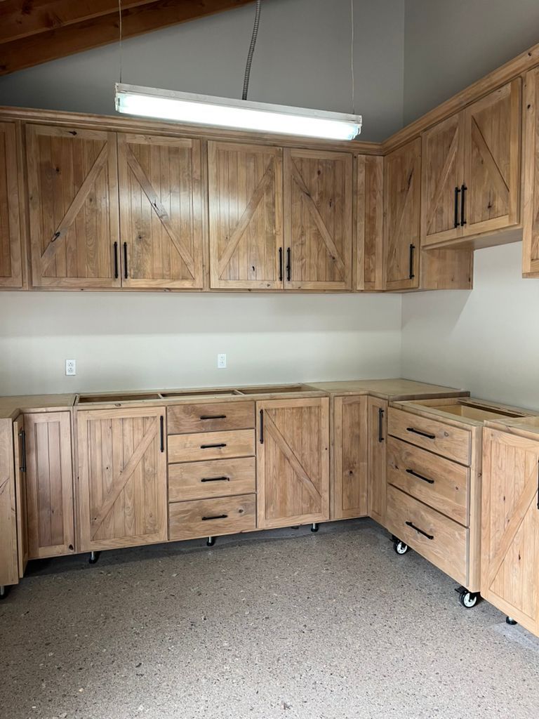 A kitchen with wooden cabinets and drawers in a garage.