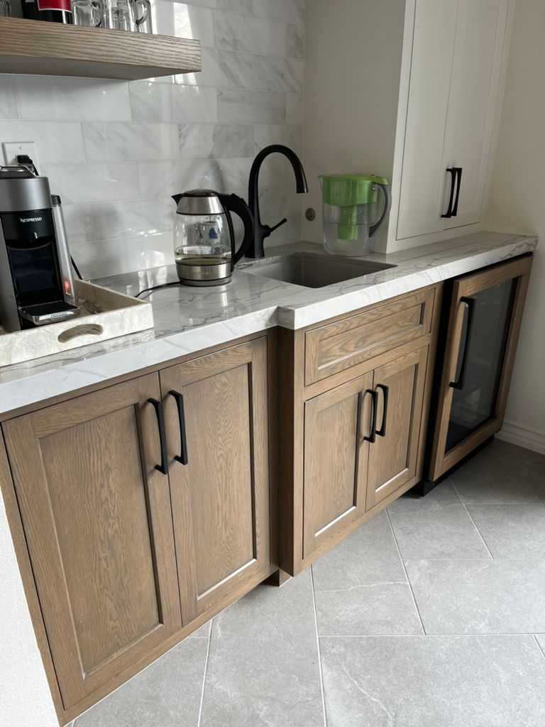 A kitchen with wooden cabinets , a sink , and a refrigerator.