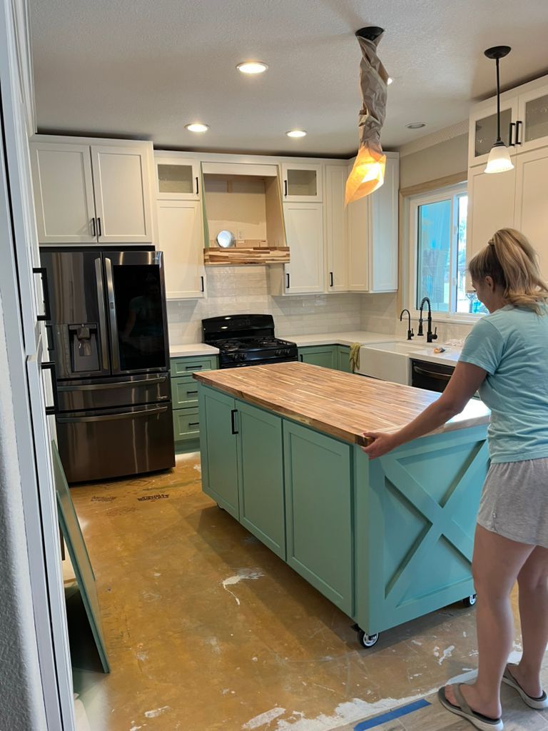 A woman is standing in a kitchen next to a large island.