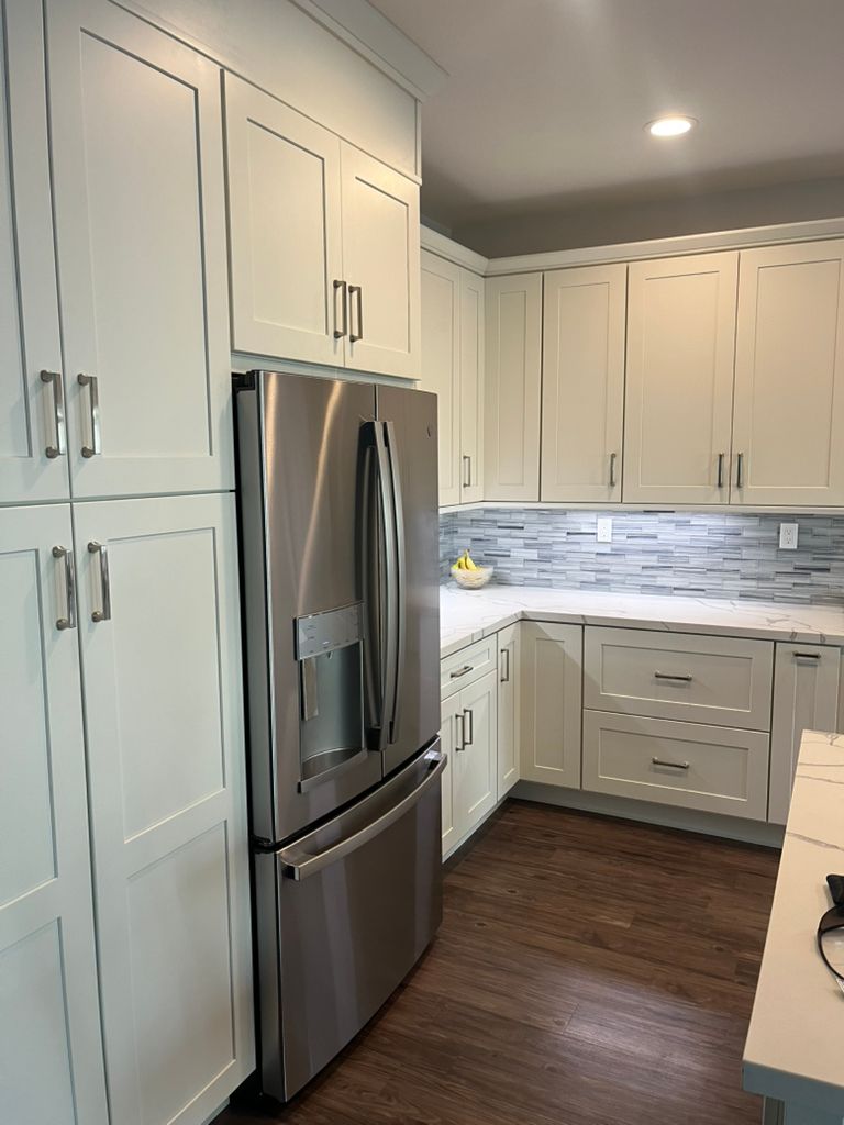A kitchen with white cabinets and a stainless steel refrigerator.