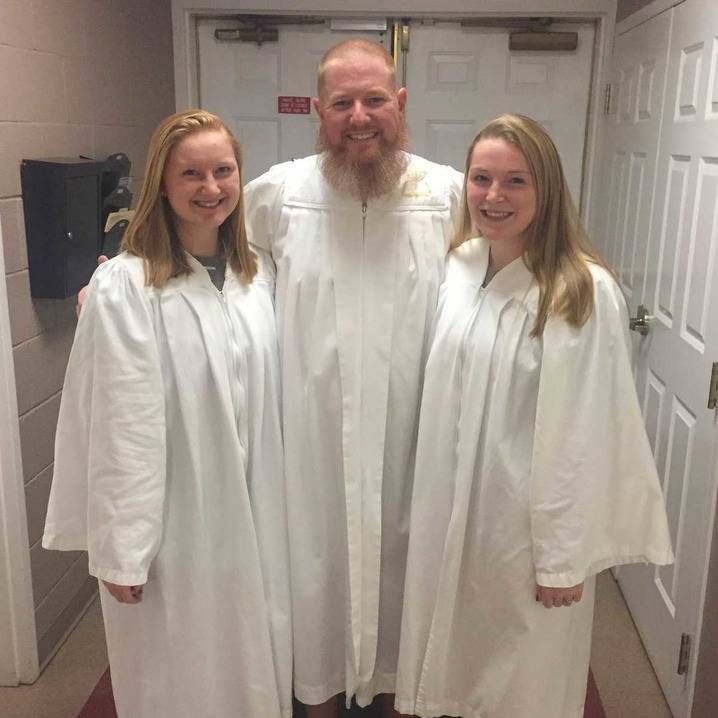 A man and two women are posing for a picture in a hallway.