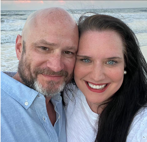 A man and a woman are posing for a picture on the beach.