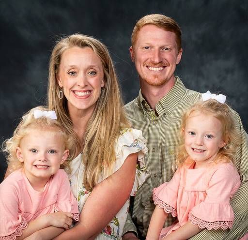 A man and a woman are posing for a picture with two little girls.