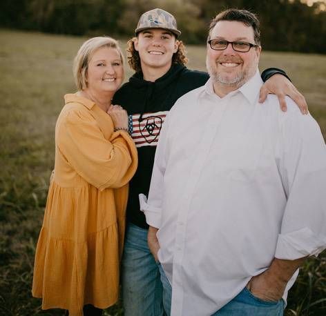 A man and two women are posing for a picture in a field.
