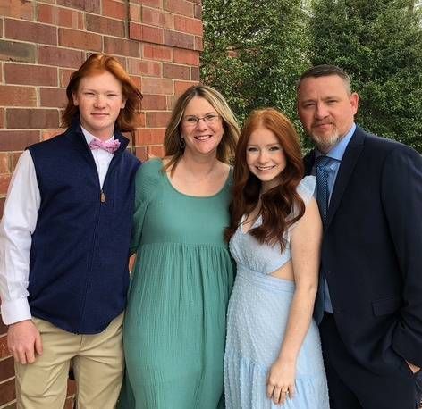 A group of people posing for a picture in front of a brick wall.