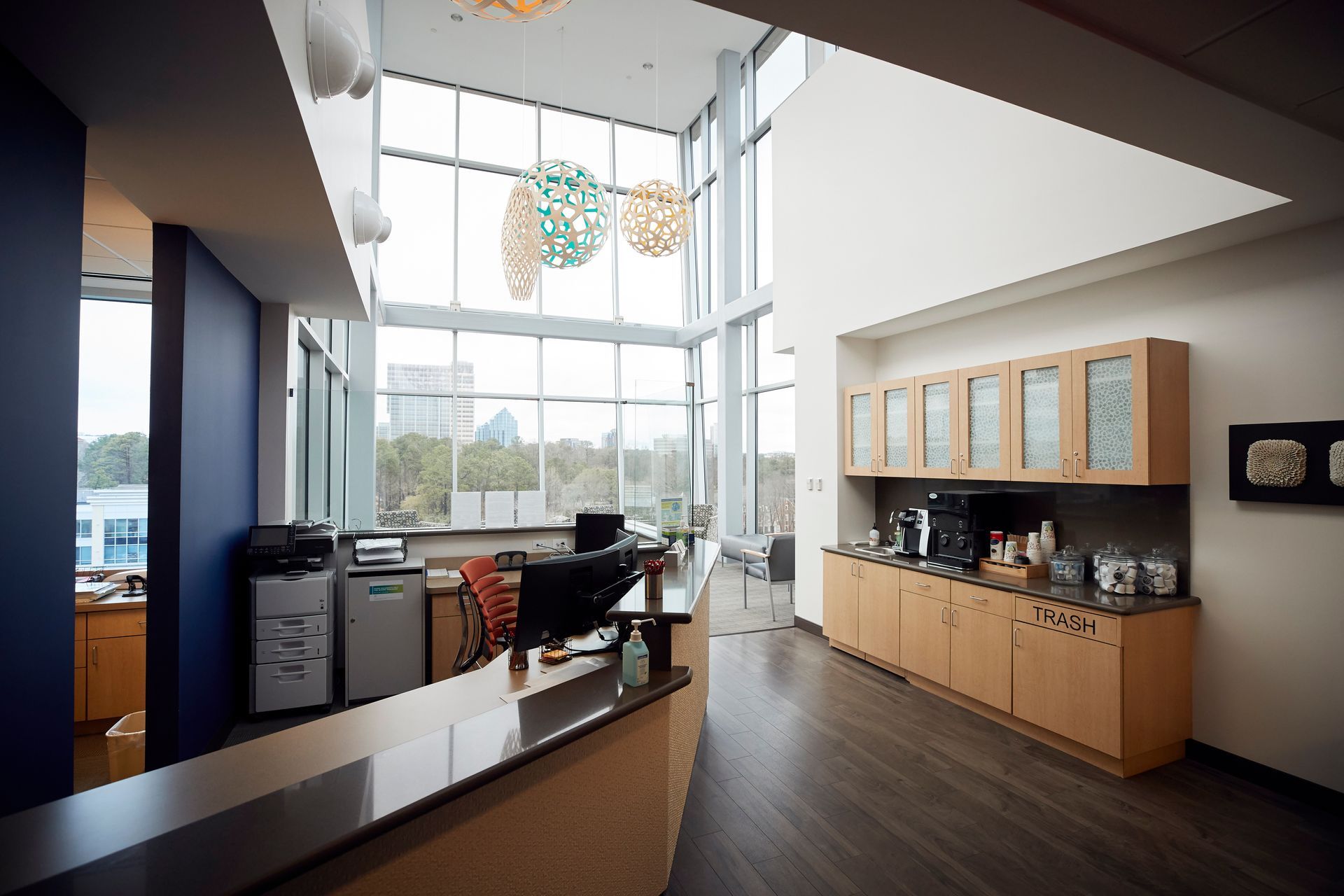 Reception area with high windows, counter, cabinetry, and coffee station.