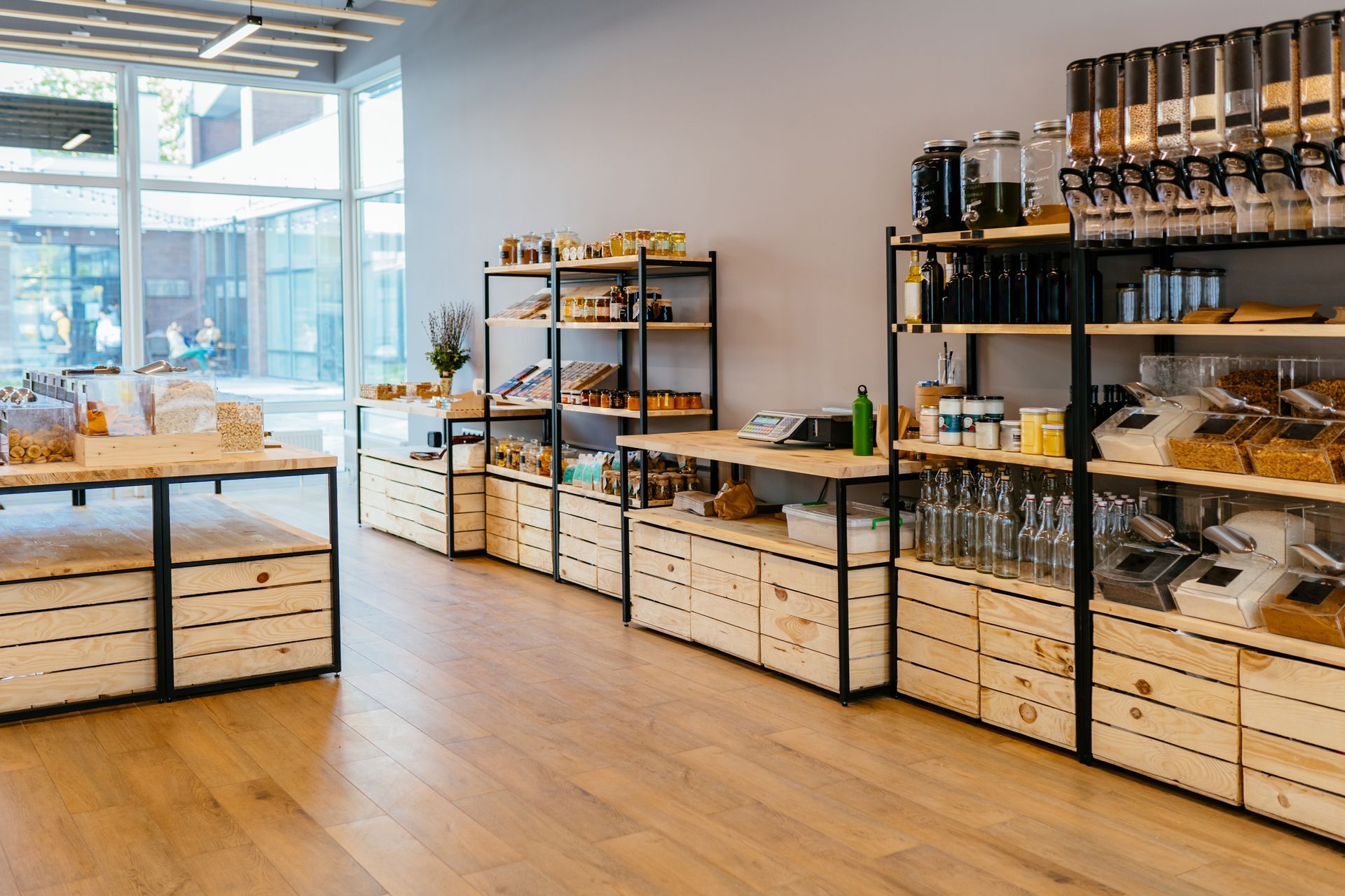 Interior of a bulk food store. Wooden shelves and crates display various products against a gray wall.