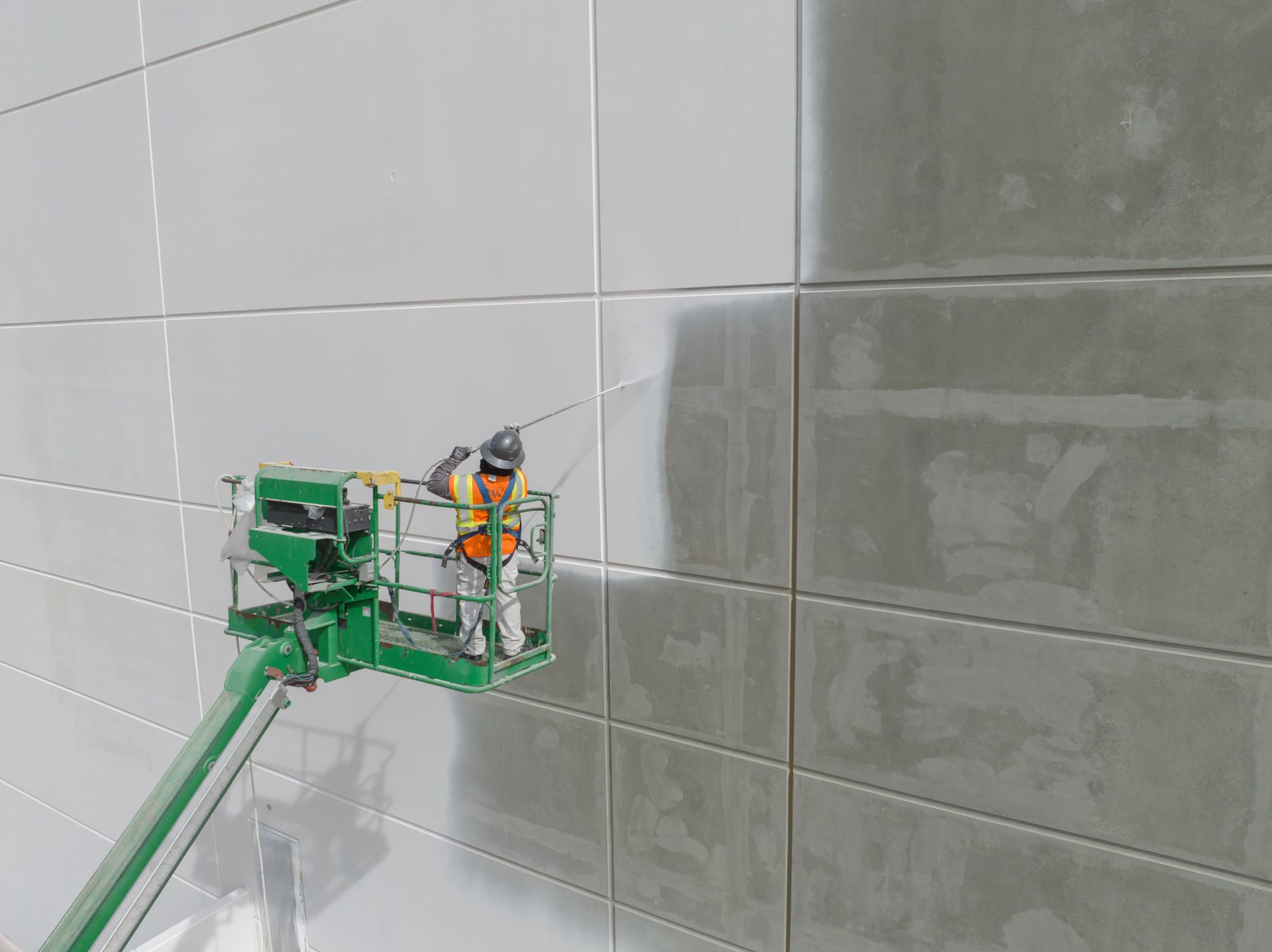 Construction worker on a lift applying material to the exterior wall of a building.