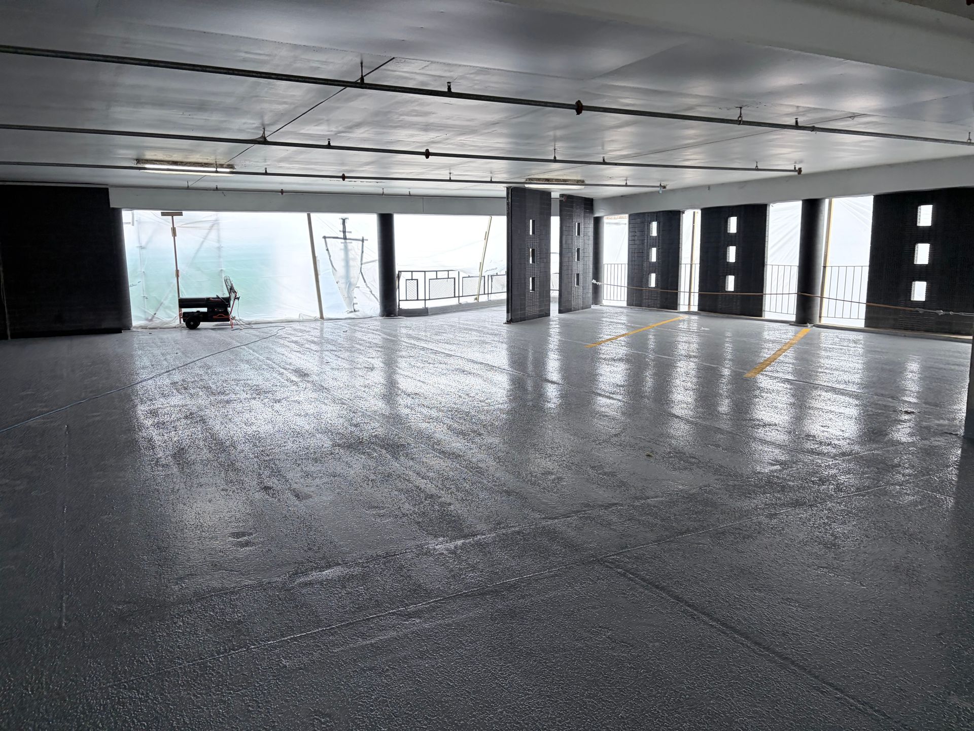 Large open space with a reflective, gray floor. Columns and open windows with a view.