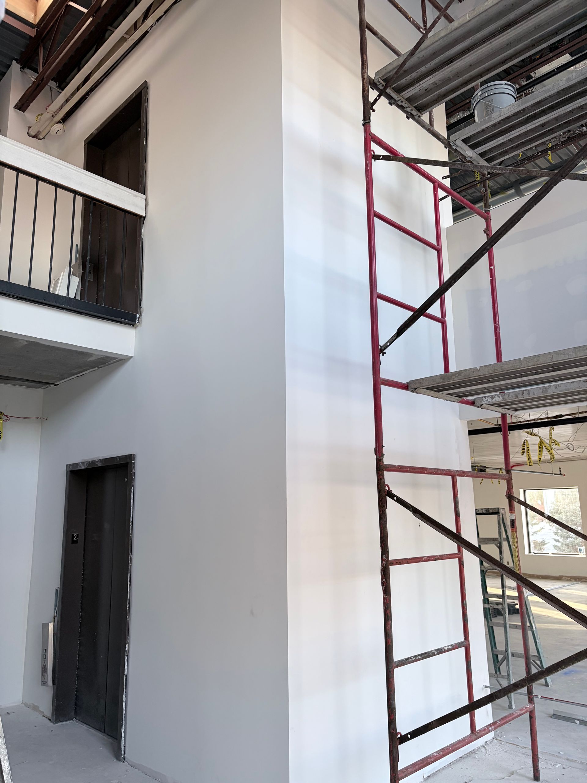 Interior with scaffolding, white walls, and dark doors.