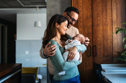 A man and a woman are holding a baby in their arms.