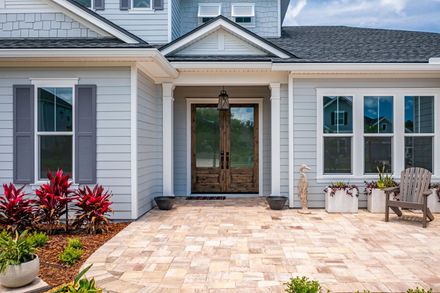 The front of a house with a patio and chairs in front of it.