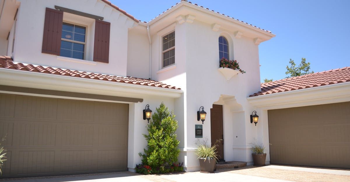 A white house with three garage doors and a tiled roof