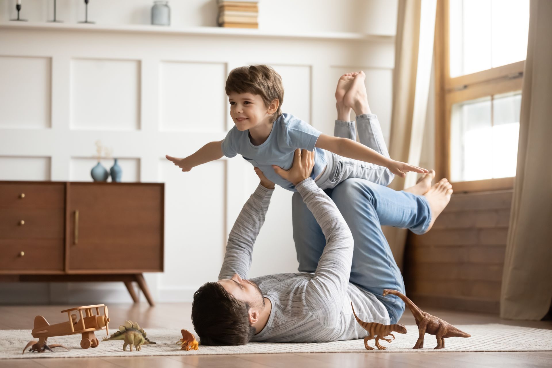 A man is playing with a little boy on the floor.