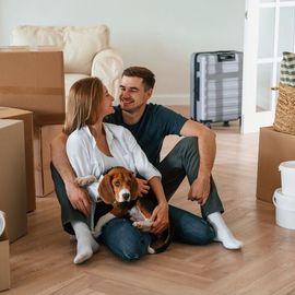 A man and woman are sitting on the floor with a dog.