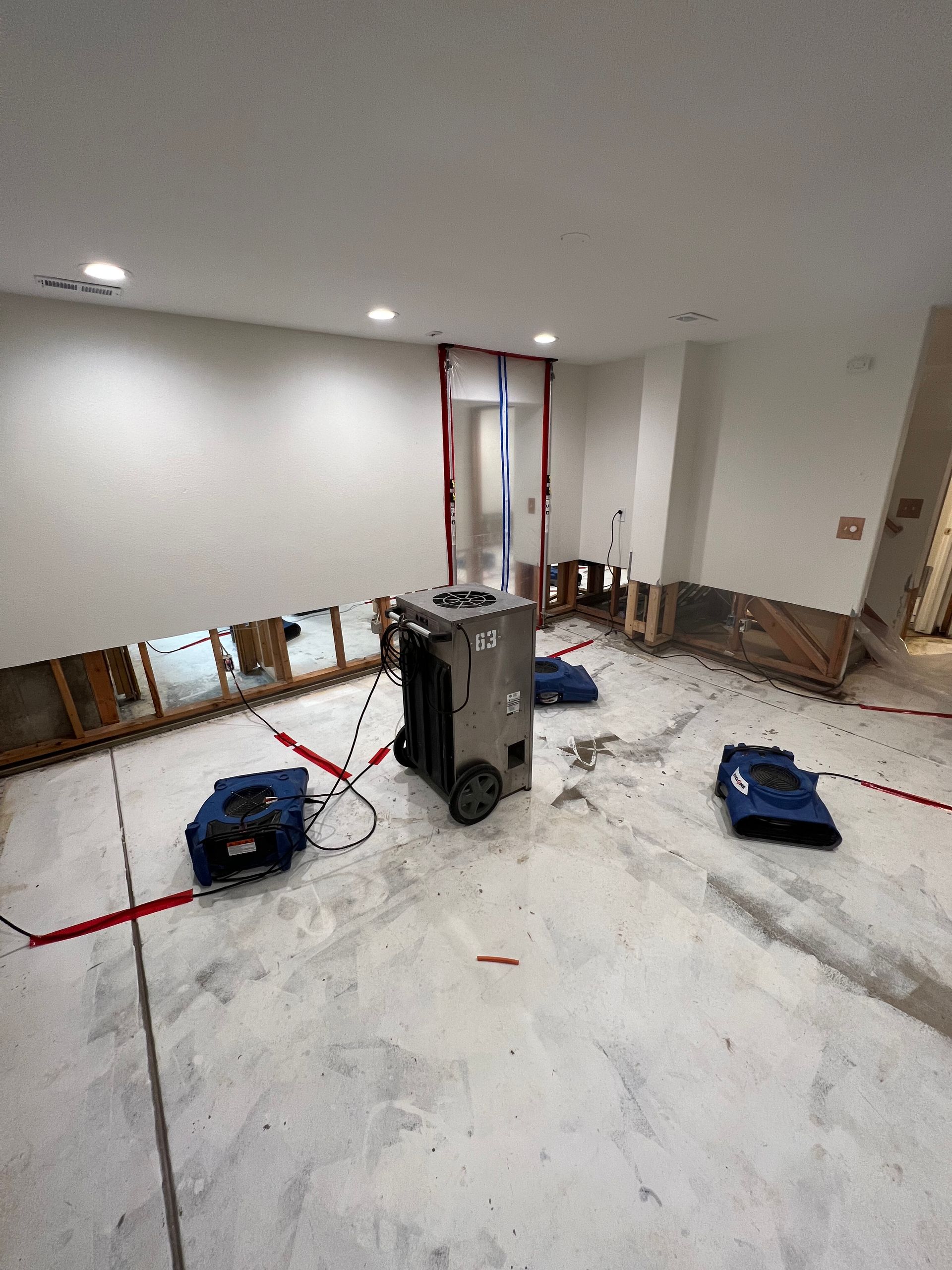 Renovated room with bare floor, exposed wall studs, tools, and a central utility cabinet under construction