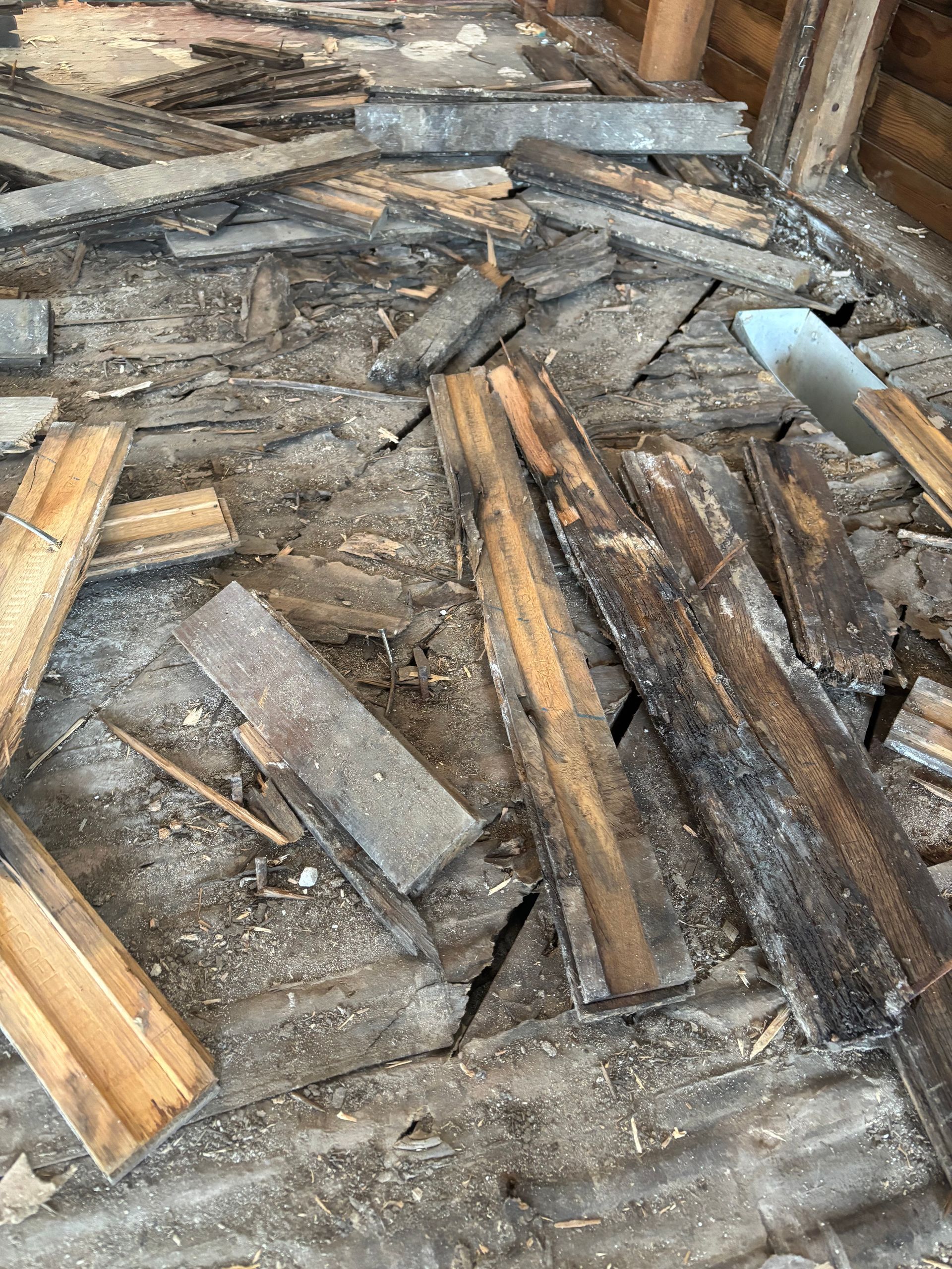 Pile of broken wooden planks and debris scattered on a rough floor.