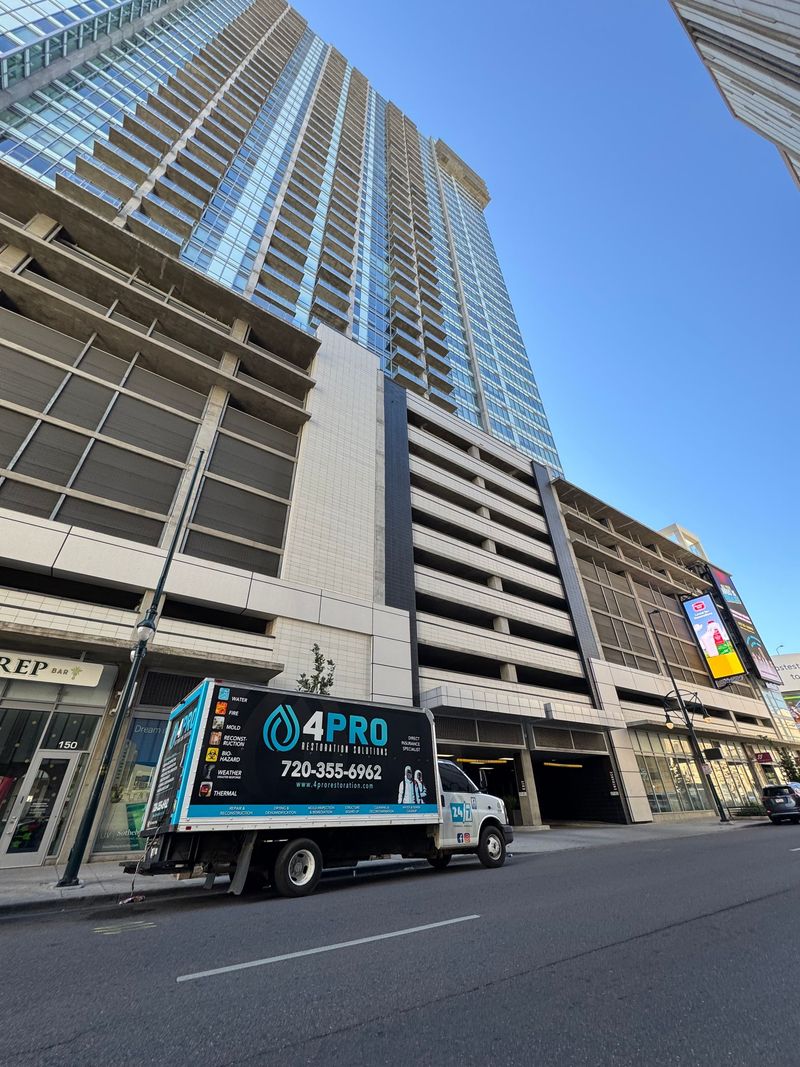 Tall city high-rise with a blue truck parked on the street below under a clear blue sky
