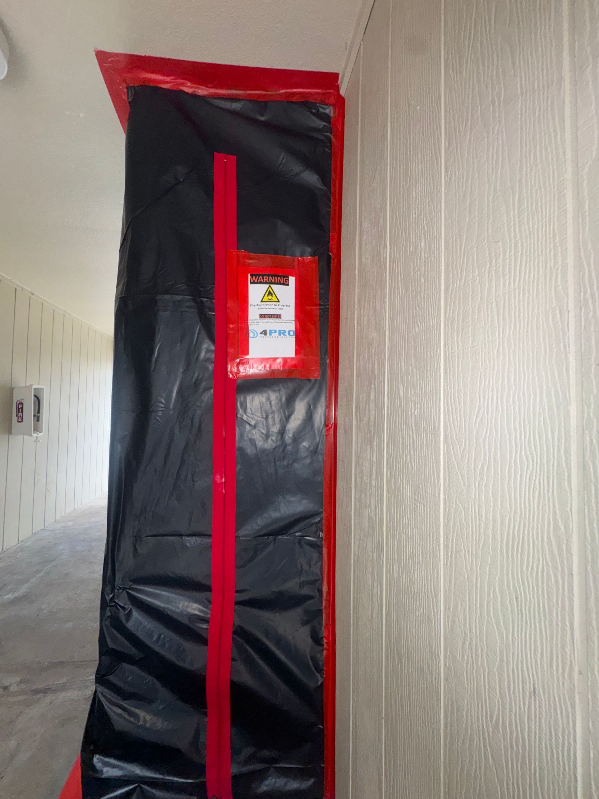 Black-and-red zippered enclosure standing in a hallway against a beige textured wall.