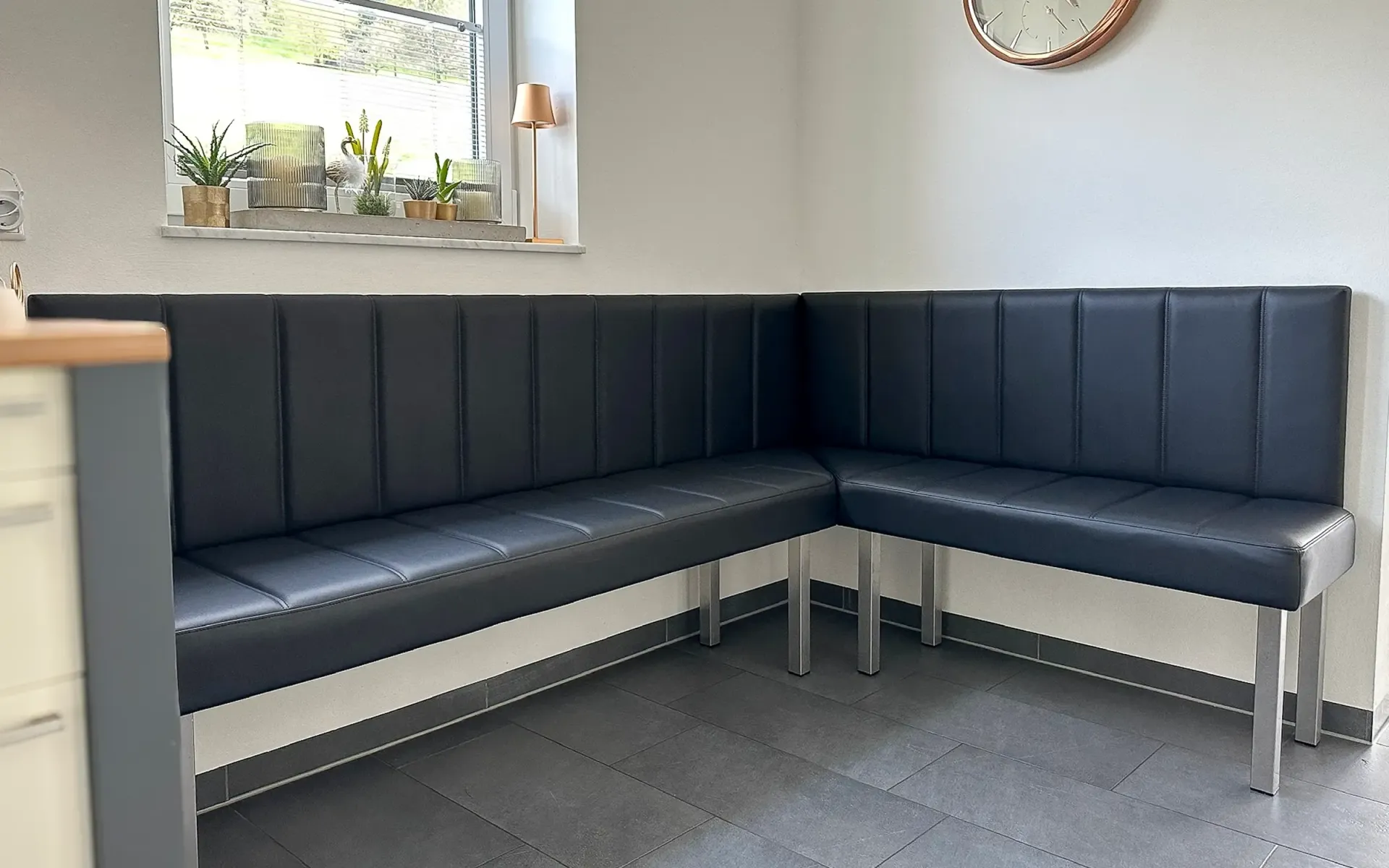 Eine moderne, L-förmige schwarze Lederbank  in einer Küchenecke 