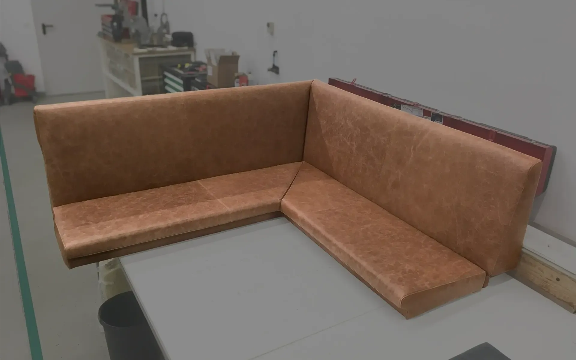 Eine L-förmige Sitzgruppe aus braunem Leder in einem Werkstattraum.