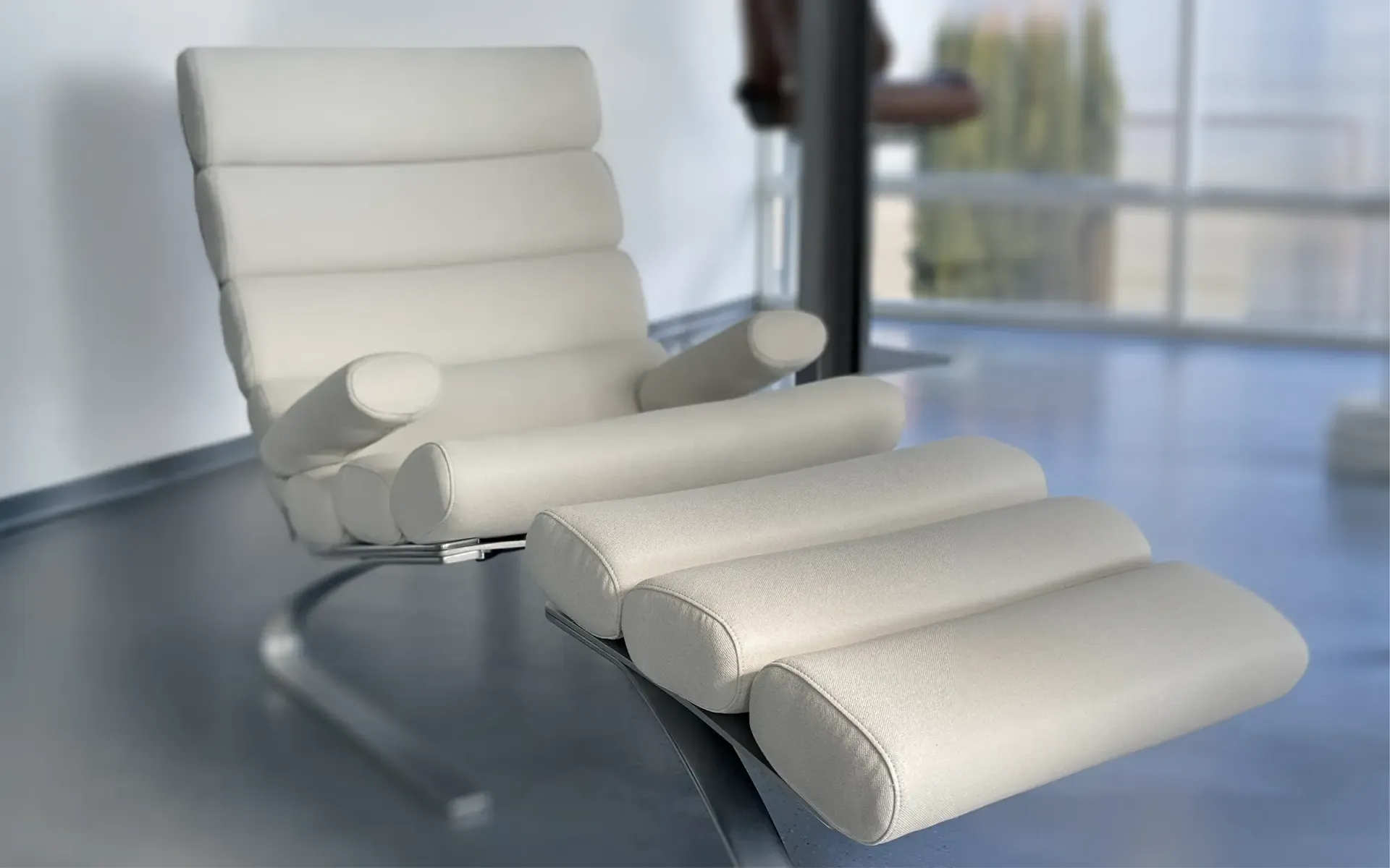 Ein weißer Ledersessel mit rohrförmigem Metallrahmen, segmentiertem Sitzkissen und verlängerter Fußstütze.