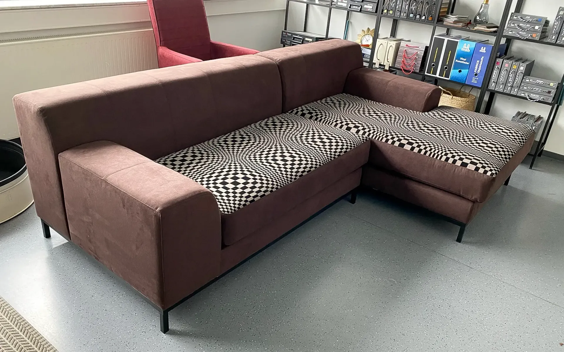 Braunes L-förmiges Ecksofa mit schwarz-weißen Kissen mit geometrischem Muster, aufgestellt in einem Raum mit einem Regal.