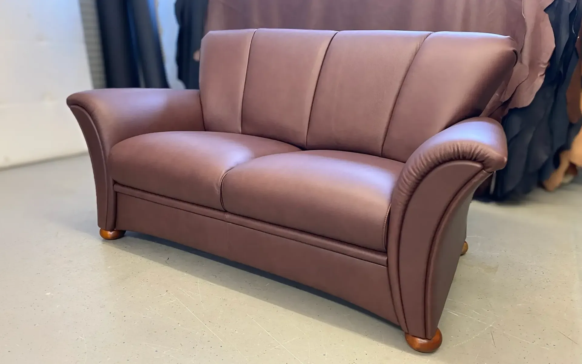 Ein zweisitziges Ledersofa in einem tiefen Rotbraunton 