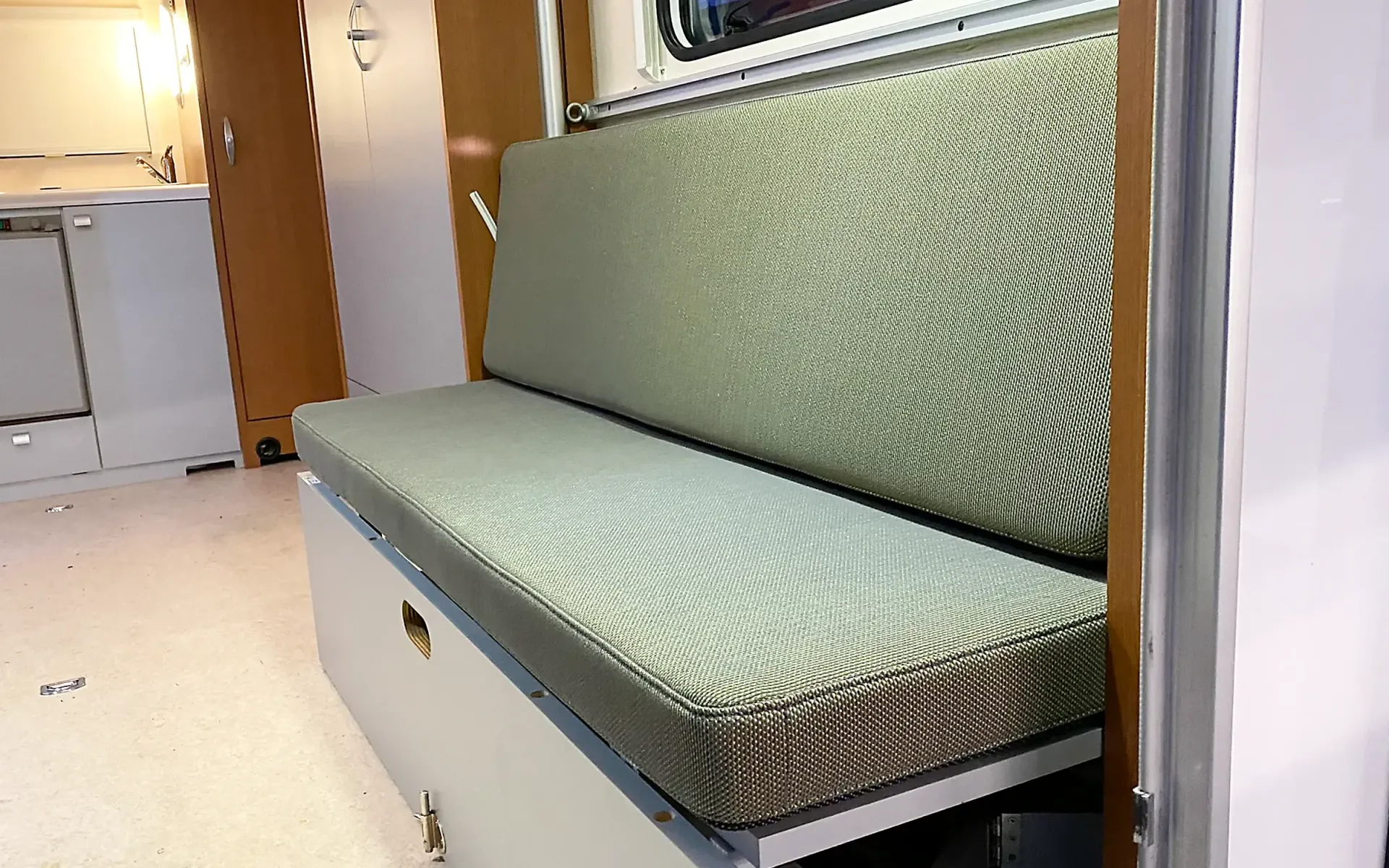 Eine strukturierte, salbeigrüne Sitzbank im Inneren eines Wohnmobils oder Wohnwagens