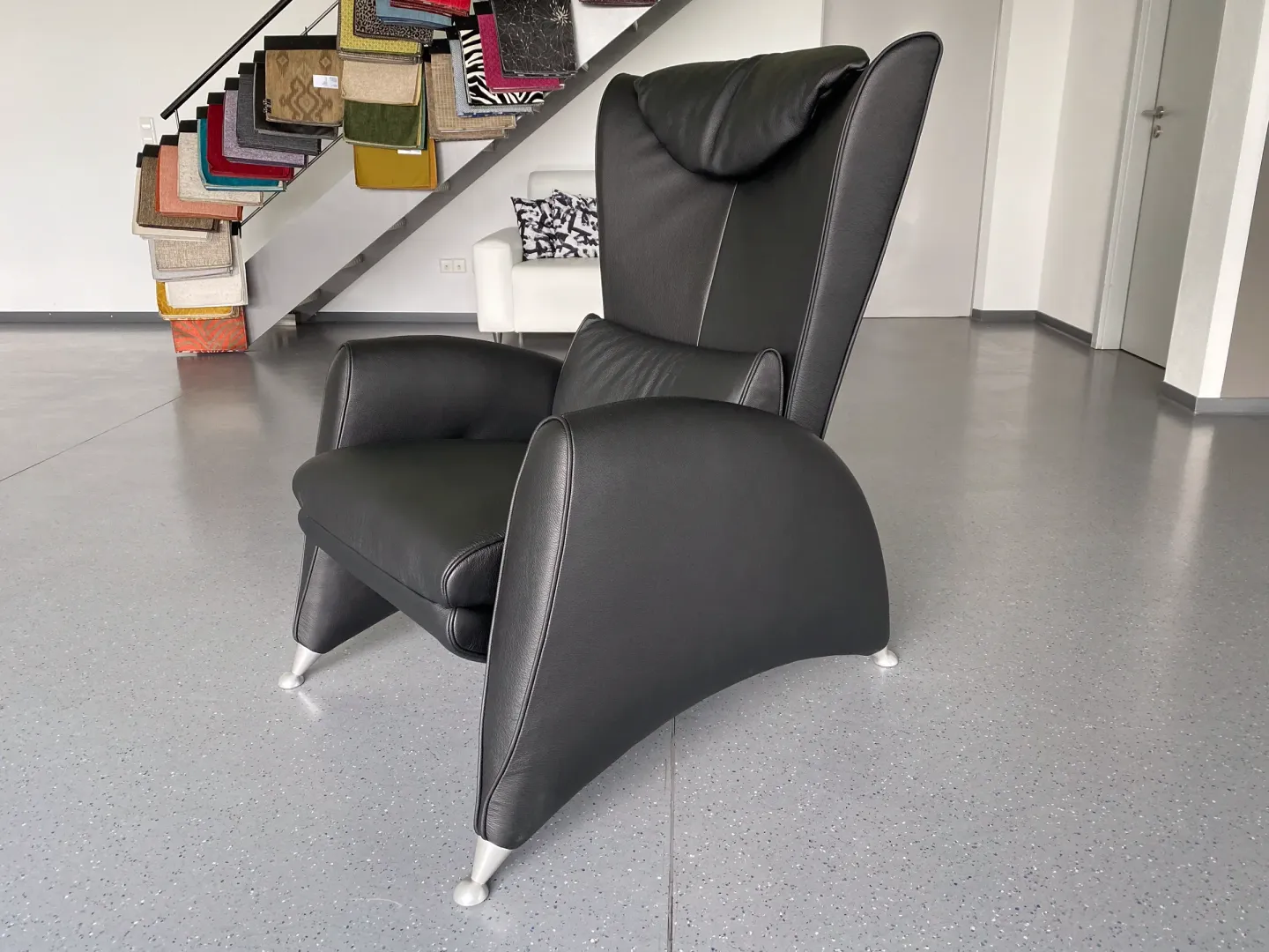 Ein schwarzer Ledersessel mit hoher Rückenlehne, gepolsterter Kopfstütze 