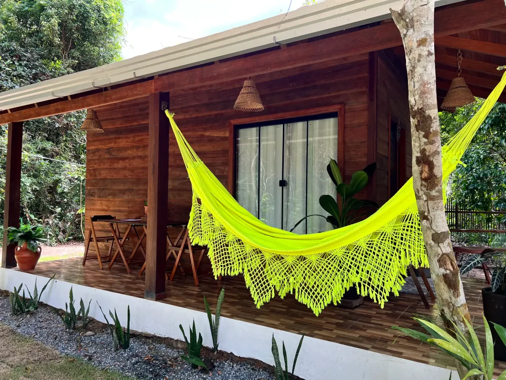 Uma casa de madeira com uma rede amarela na varanda.