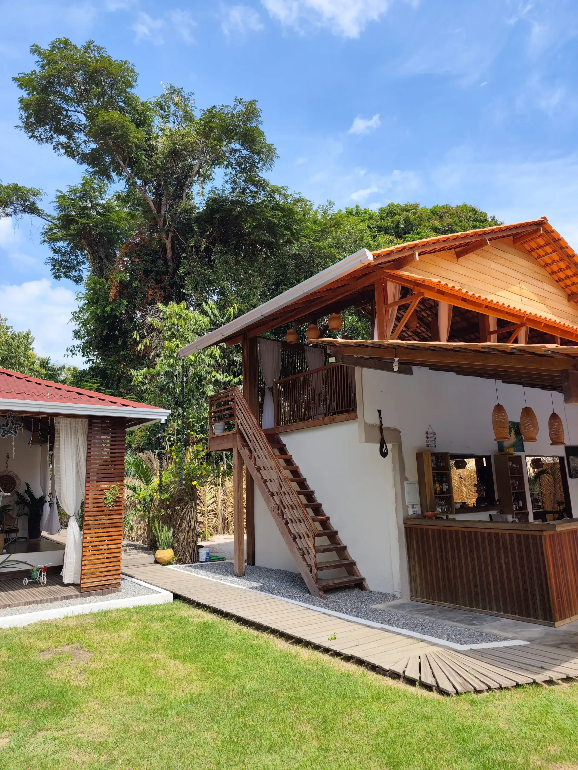 Uma casa de madeira com escadas que levam até ela, cercada por árvores e grama. Pousada-Sumaúma