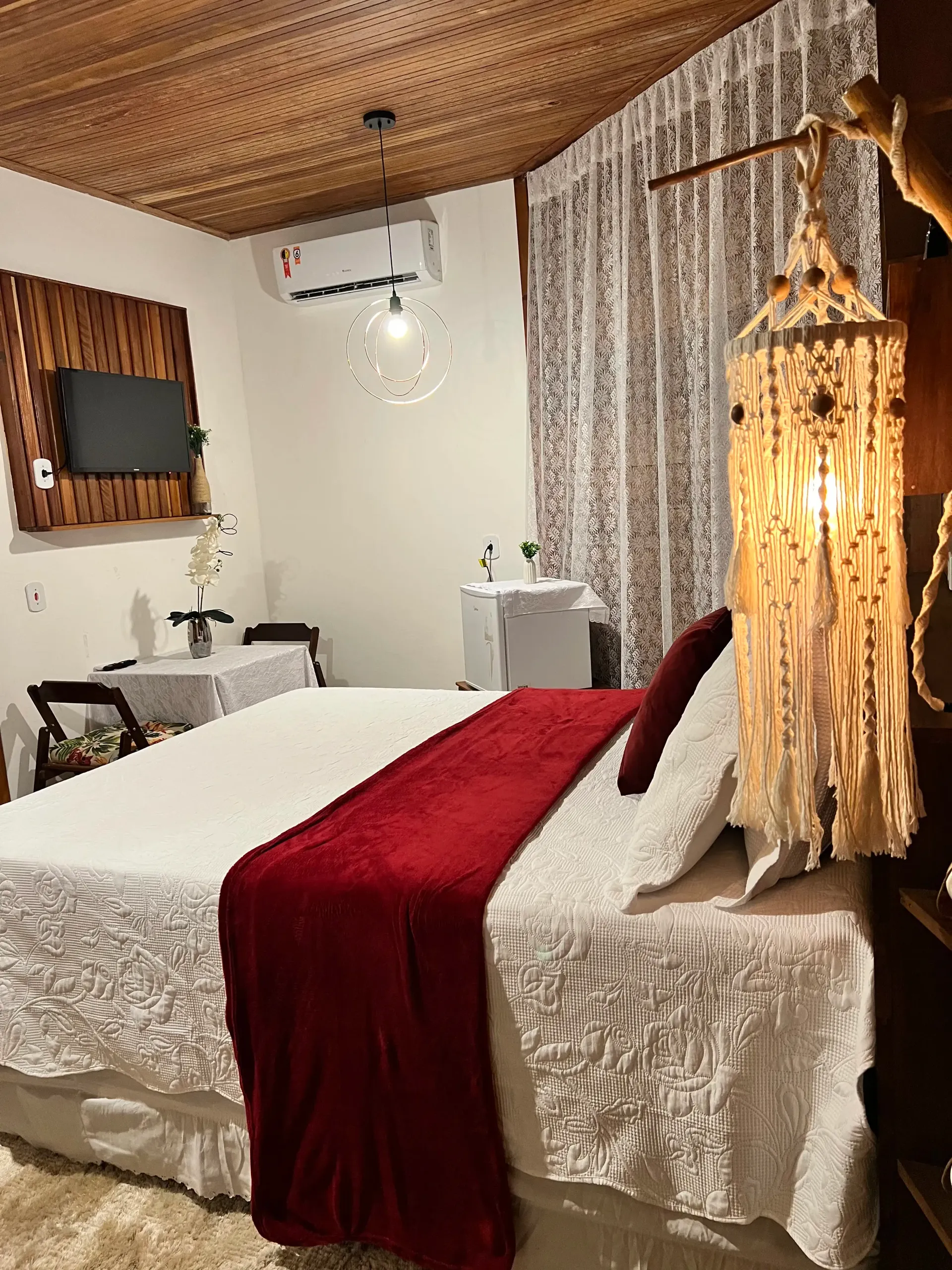 Um quarto com uma cama grande e um cobertor vermelho. Pousada-Sumaúma