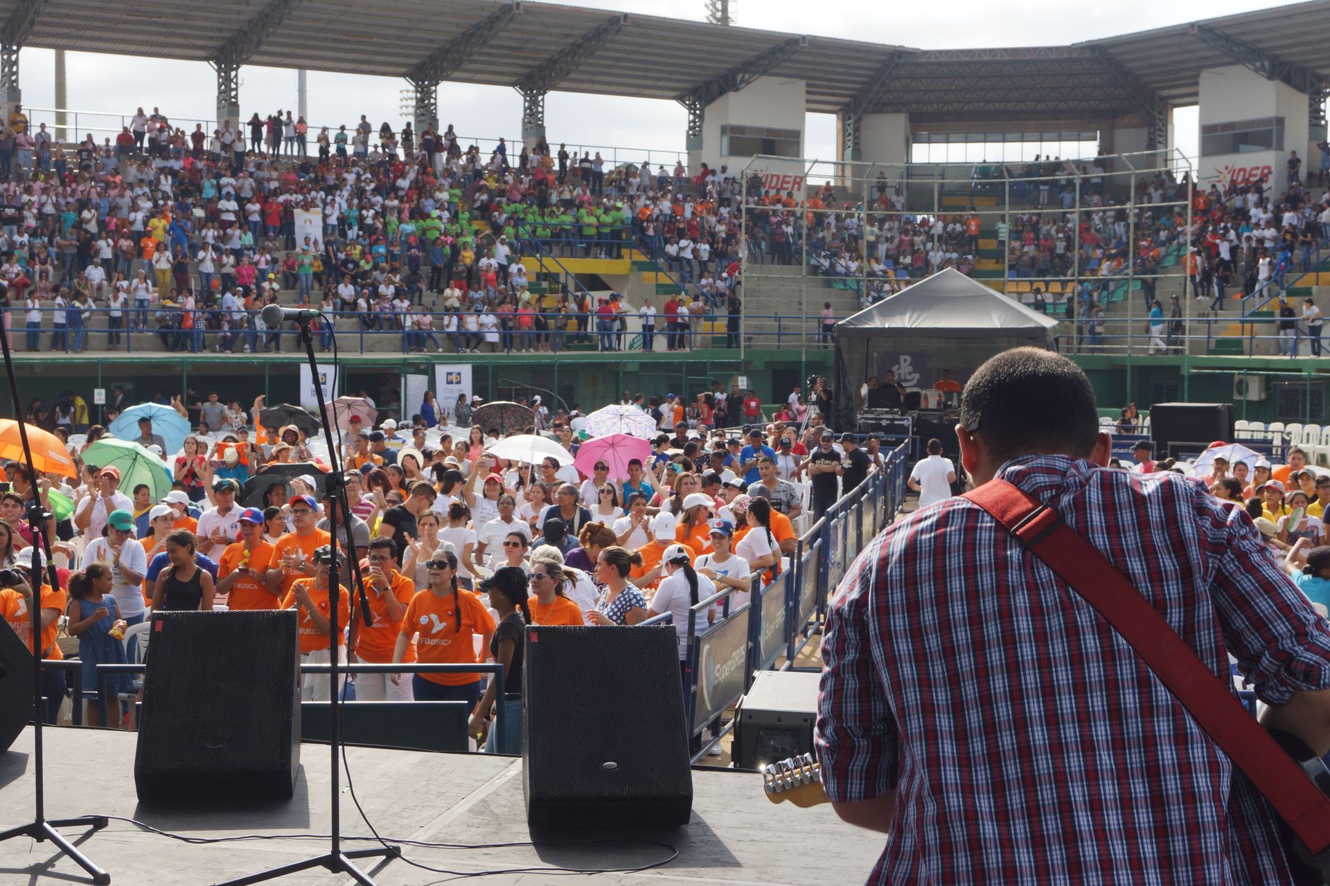 Un guitarrista en el escenario de un estadio se enfrenta a una multitud numerosa 