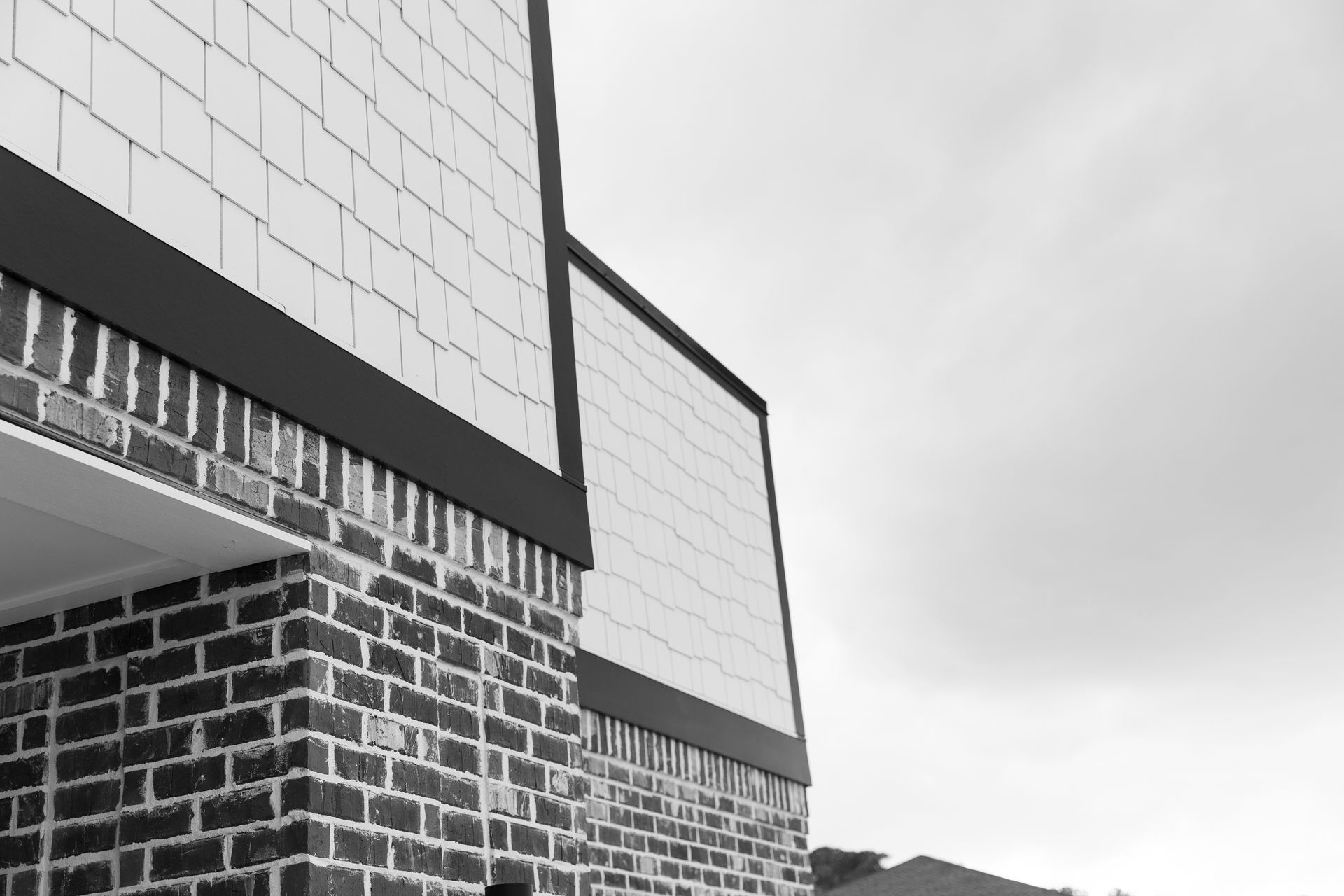 Brick building with white tiled accents under a cloudy sky.