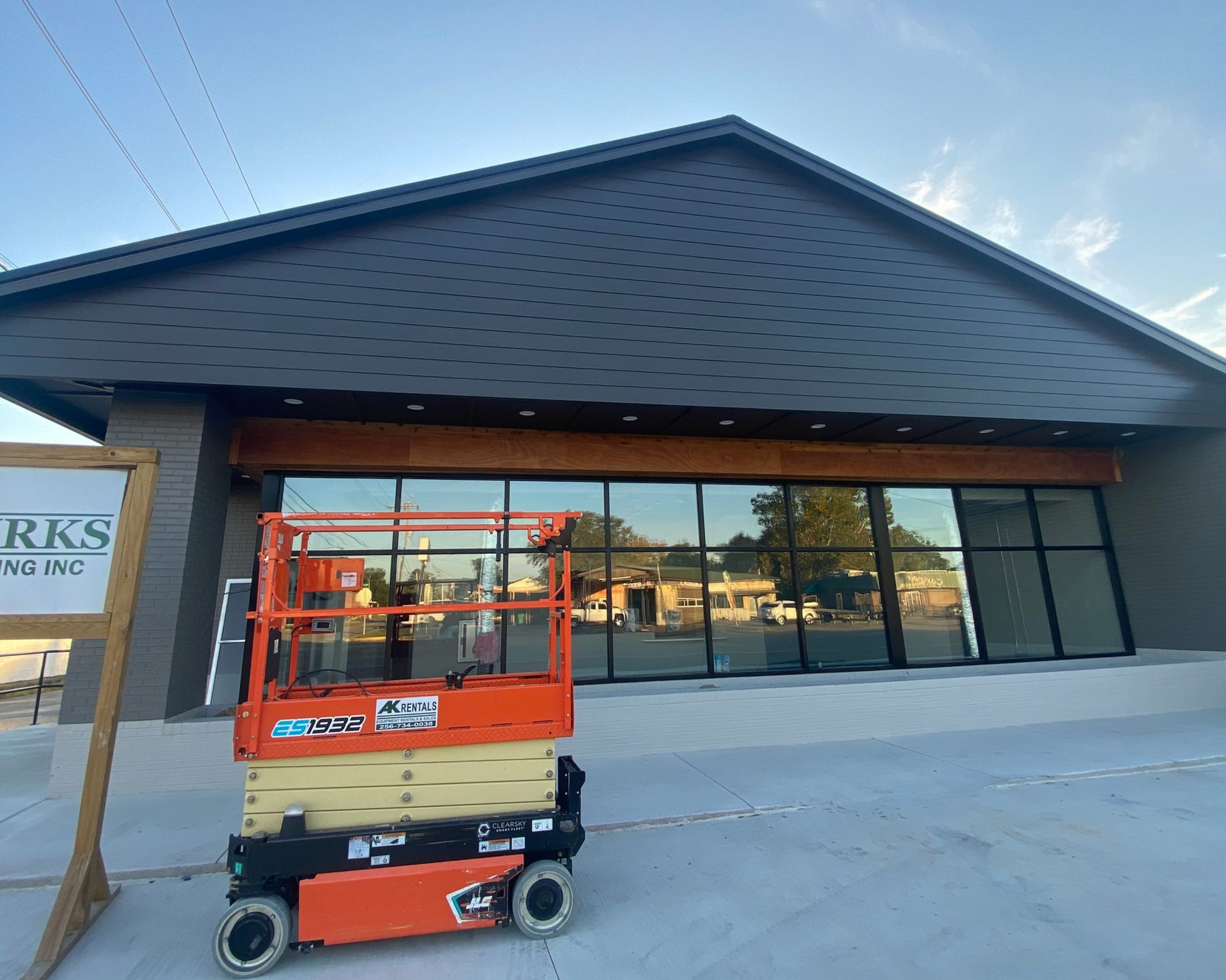 An orange lift in front of a modern building with large windows and a dark roof.