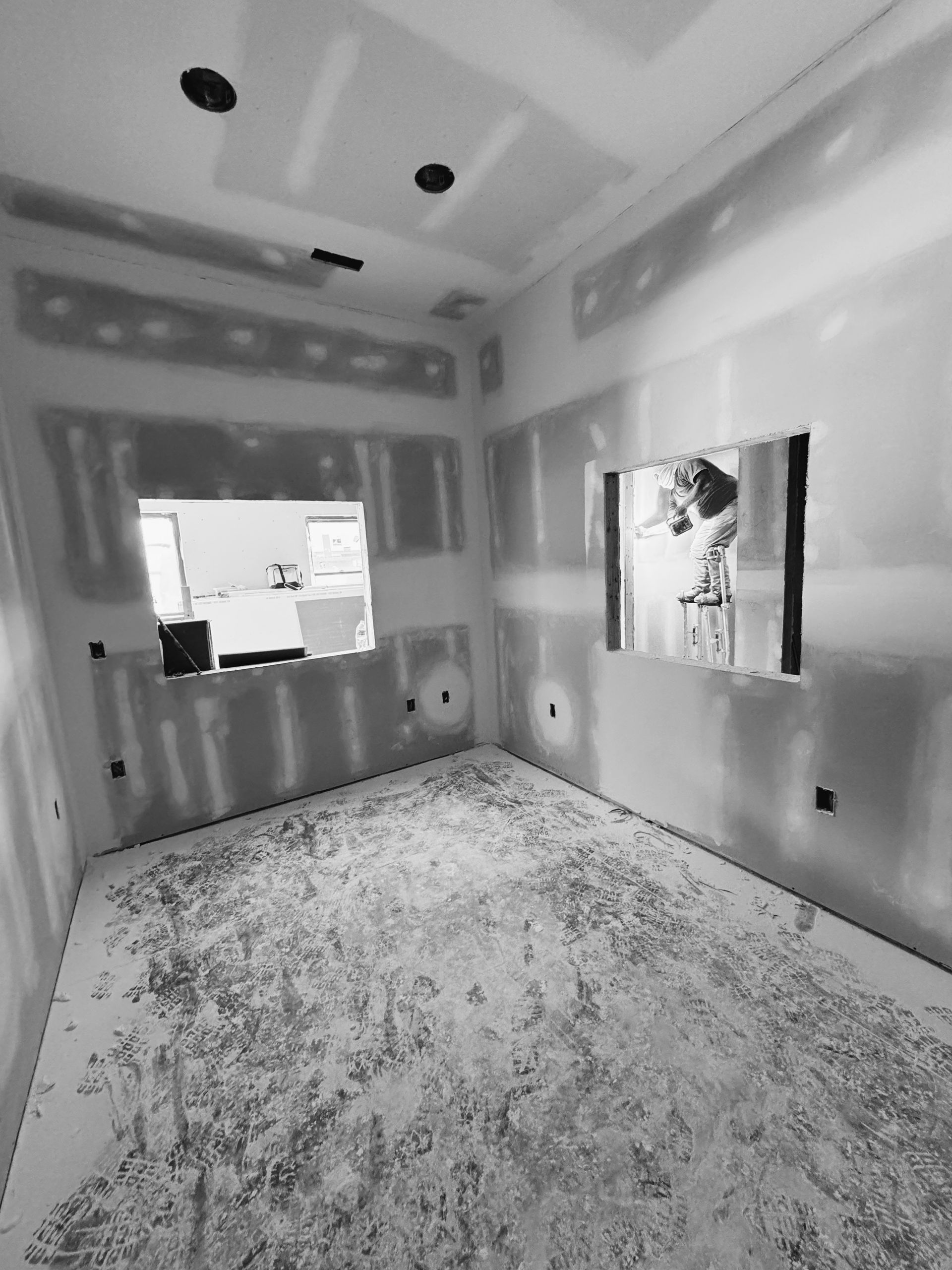 Interior room under construction with drywall and window openings.