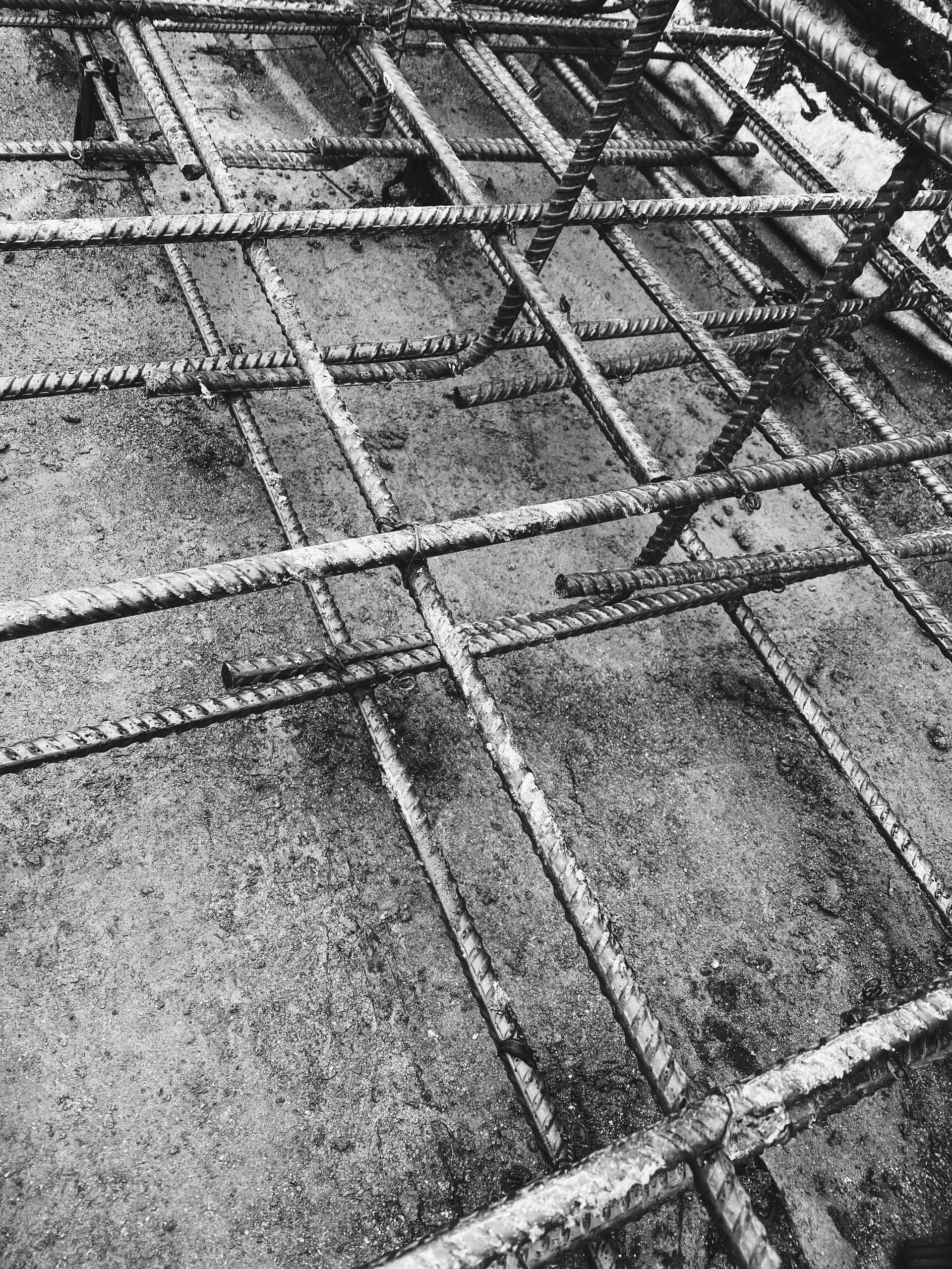 Reinforcing steel bars arranged in a grid on a concrete surface, ready for concrete pouring.
